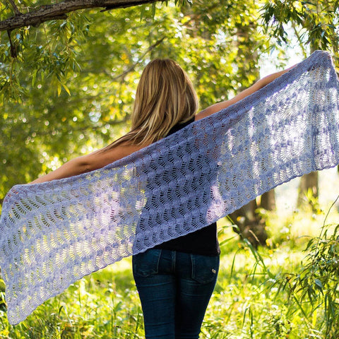 A woman is facing away from the camera, the periwinkle silk shawl around her shoulders. 