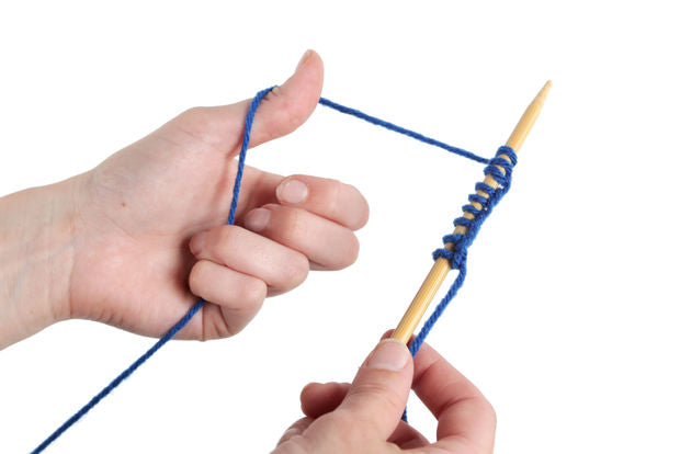 hand holding a needle and yarn