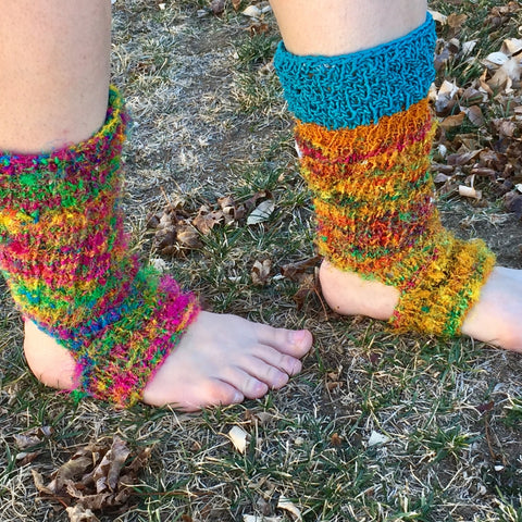 Two pairs of feet are standing in the grass, wearing colorful leggings.