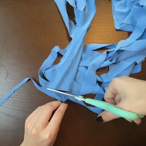 Using the scissors, cut diagonally against the strips of blue strands to create a continuous strand of t-shirt yarn