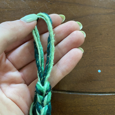 A hand is holding a thick chain of sparkle worsted weight yarn that has a large loop at the tail end of the chain.