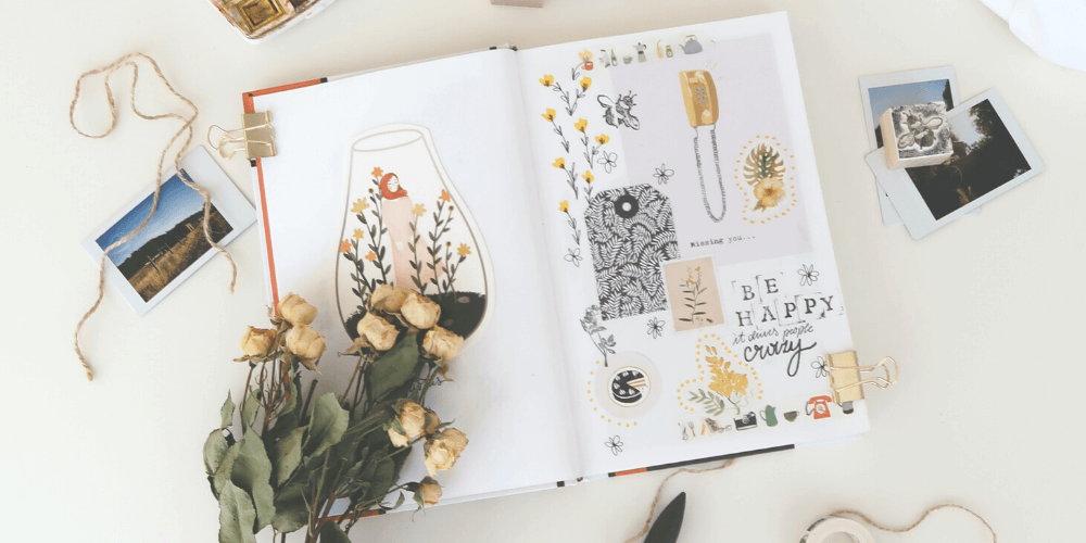 Scrapbook on white table with dried white roses