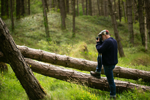 Mann mit Patchwork-Schiebermütze fotografiert im Wald