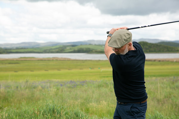 Mann spielt Golf und trägt eine Schiebermütze aus Leinen