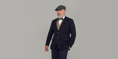 Ein Mann trägt Anzug, Weste, Tweed-Fliege und Tweed-Schiebermütze