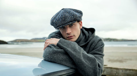 Man leaning on car wearing a newsboy style cap