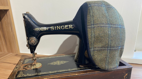 Donegal Touring Duo Cap Tweed sitting on a vintage Singer sewing machine