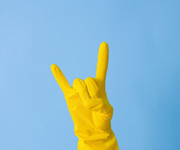 Hand with yellow playtex glove on giving the rock out sign with fingers