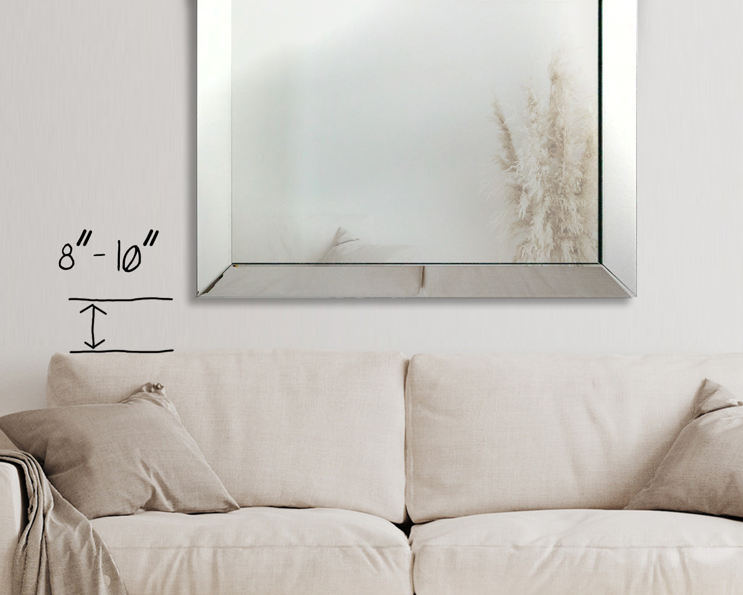 a picture of a large mirror hung above a couch showing to hang it 8 to 10 inches above the back of the couch