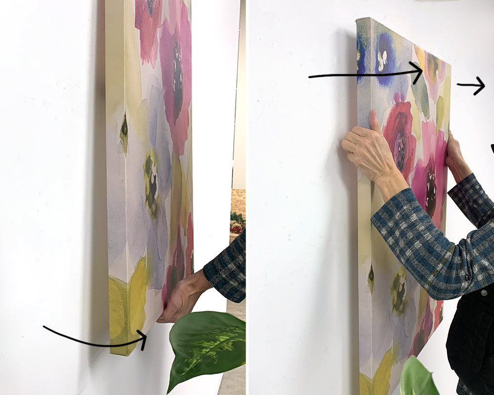 two pictures, the first showing a person gently pulling the bottom of a canvas art away from the wall; the second picture is a person putting their fingers between the canvas art and wall about 1/2 way up and pulling the canvas art directly away from the wall 