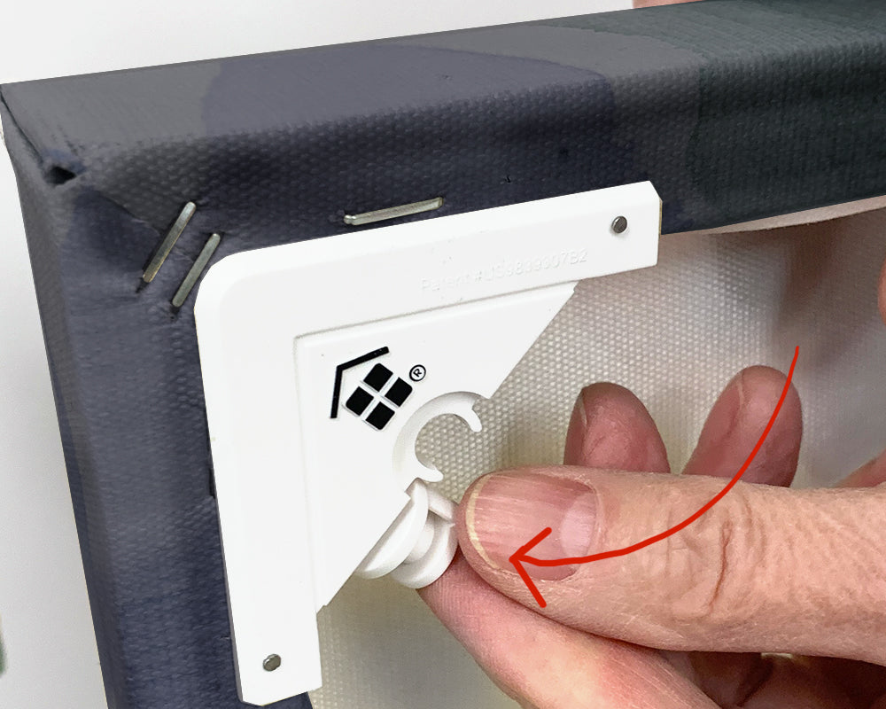 Image showing the back side of a canvas art installed with Canvashangers™ and an arrow showing where to place the pin in the holder so its safe while the canvas is not on the wall.
