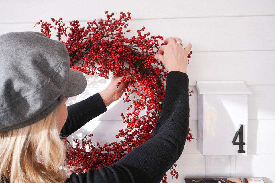 Woman styling a red holiday wreath