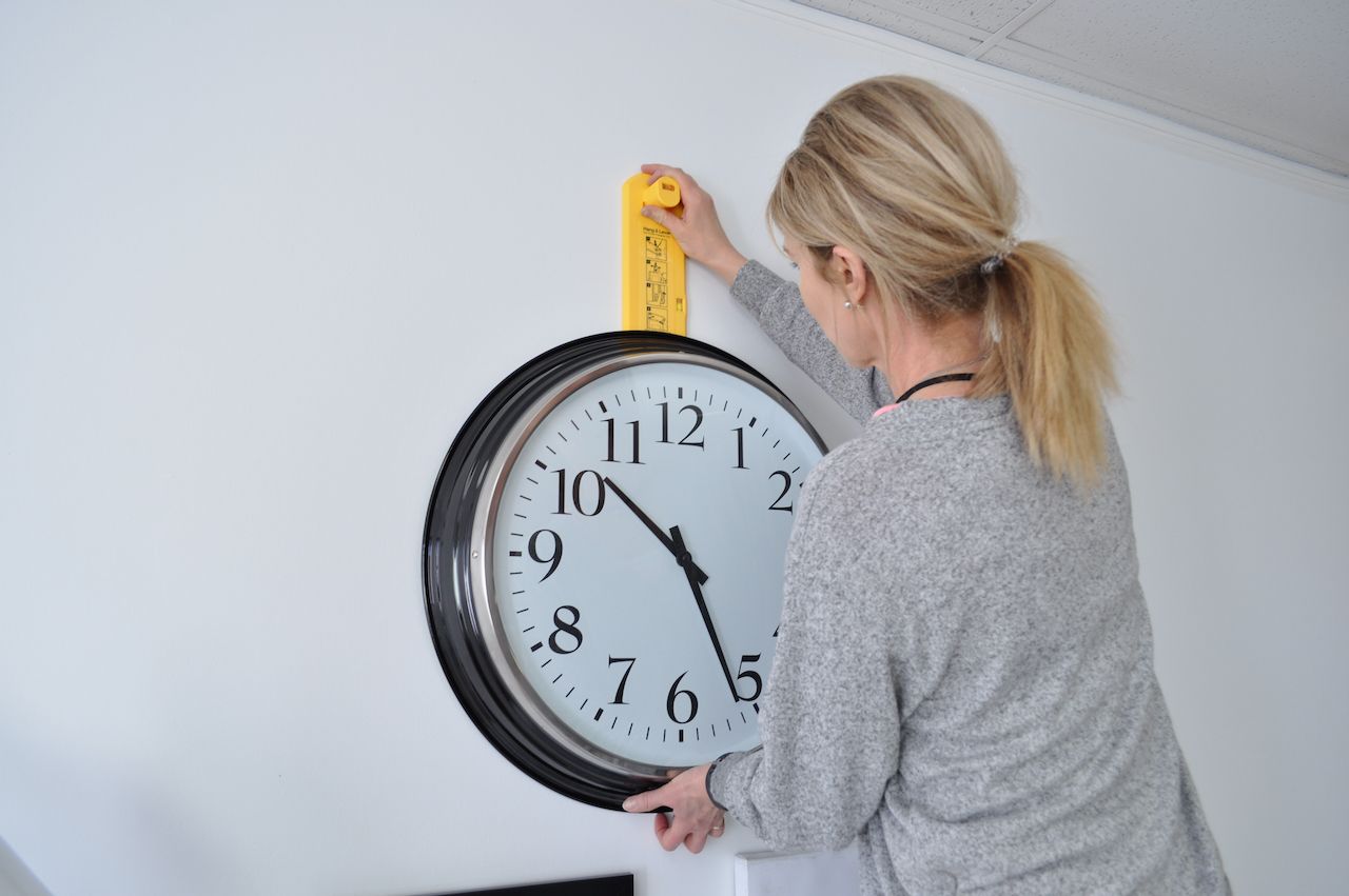 woman hanging clock with Hang&Level