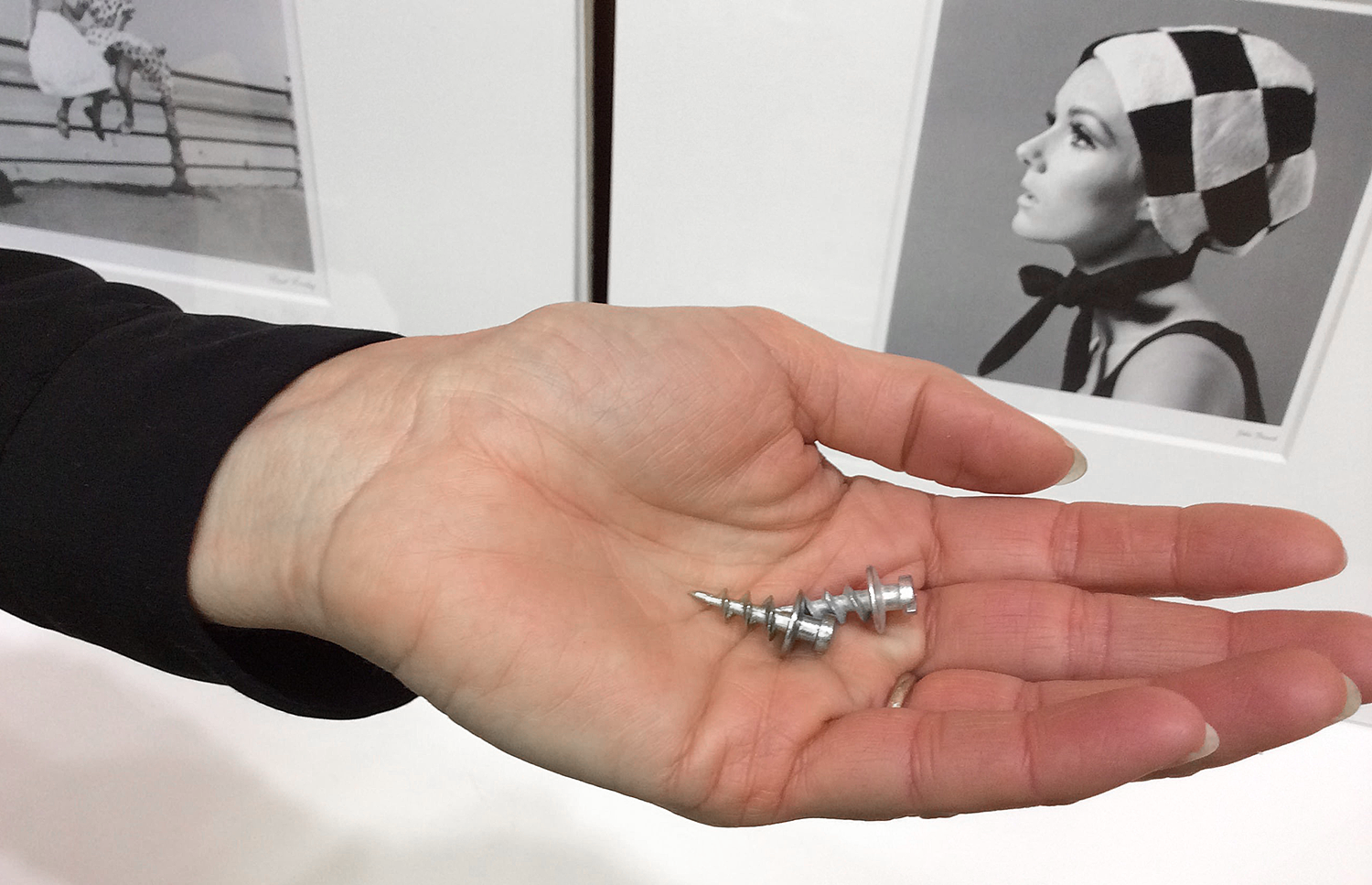 A picture of a person holding 2 DecoScrews in her hand. They securely hold up to 30 lbs in drywall so she is using them to hang a heavy mirror. 
