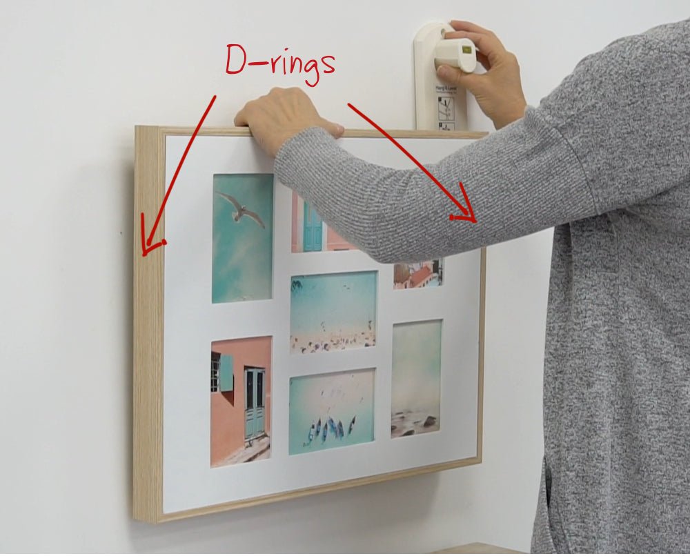 Person using Hang & Level™, the picture hanging tool, to mark exactly where to mark the nails on a picture installed with two D-ring hangers.