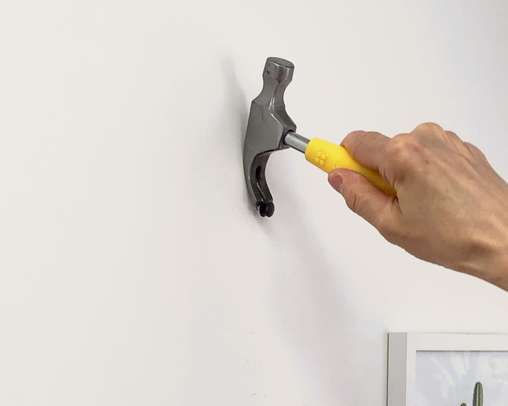 Person using drywall spackle to fill a picture hanging nail hole in drywall.