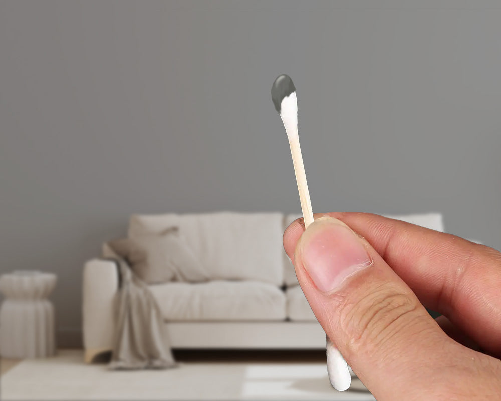 picture of a person holding a Q-tip with paint that matches the wall in the background.