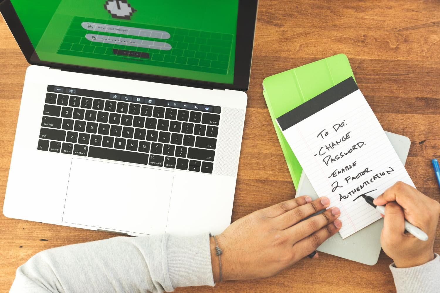 Una persona scrive una lista di cose da fare su un taccuino, tra cui cambiare la password e abilitare l'autenticazione a due fattori per garantire la sicurezza dei suoi account.