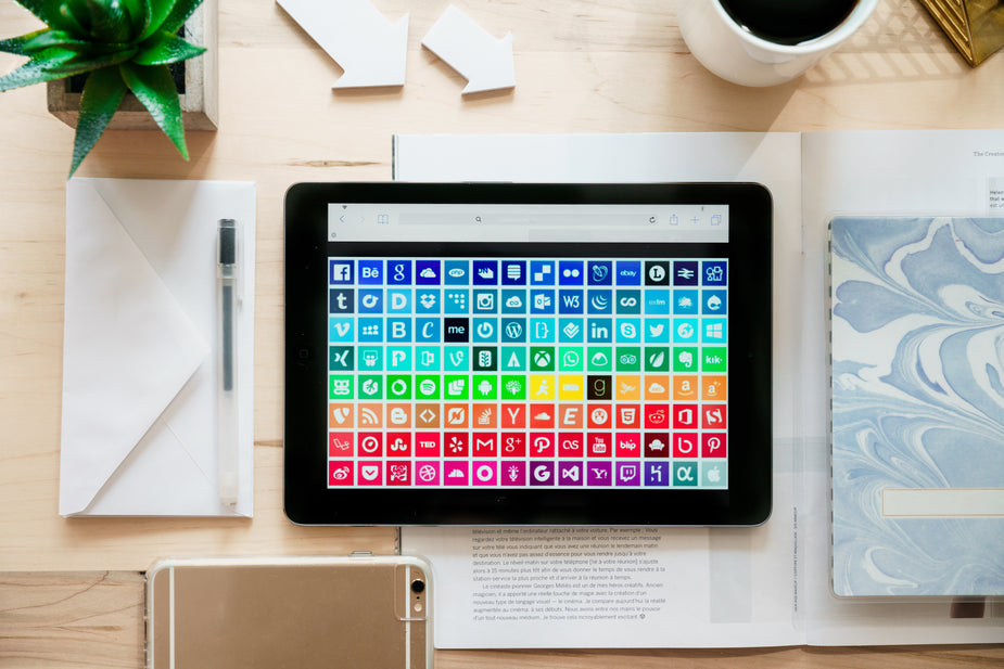 Flatlay con tablet che mostra icone social e strumenti di marketing digitale