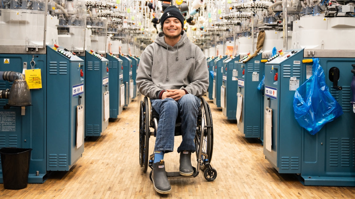 Trevor Kennison seated in his wheelchair in the Darn Tough mill, smiling away