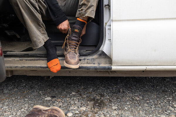 Person putting on leather work boots over the Steely work socks from darn tough