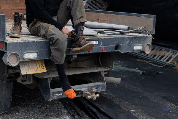 Person pulling on leather work boots over Darn Tough Work Socks