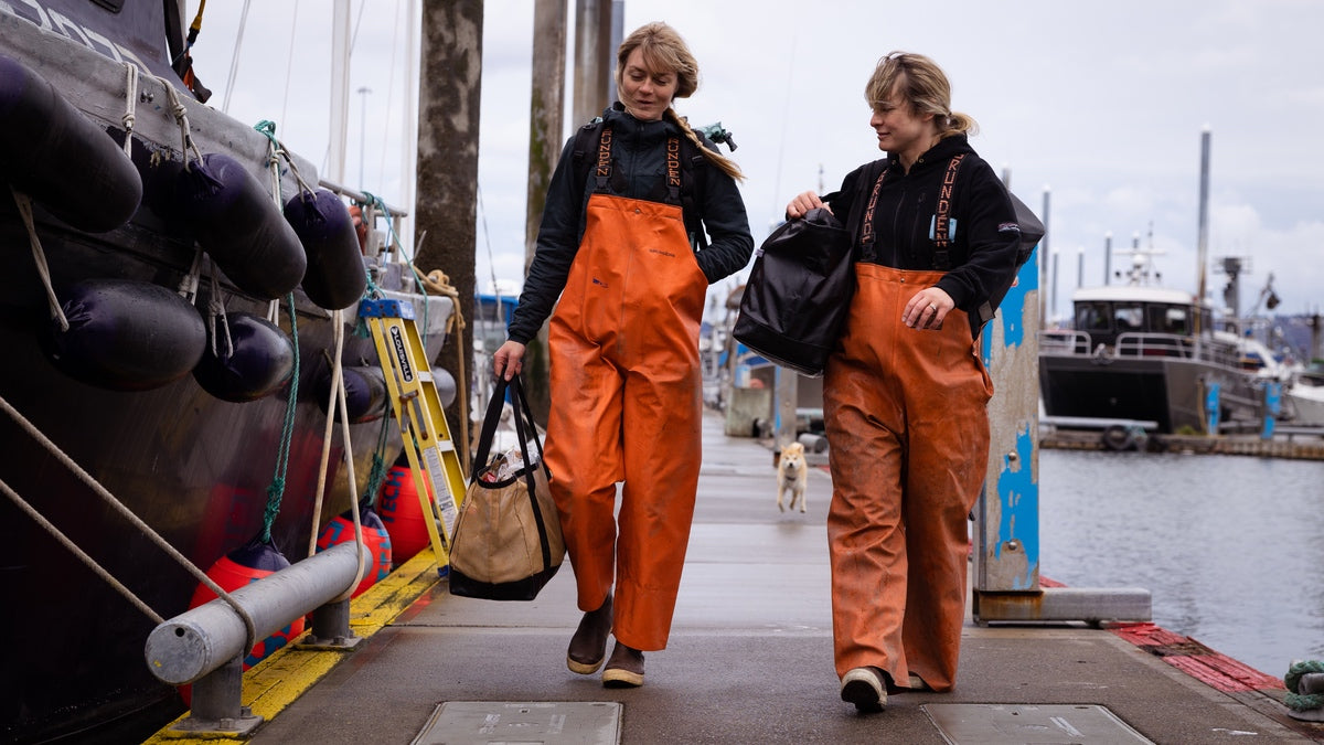 Emma and Claire, the Salmon Sisters, walking down a wharf in Alaska wearing their fishing gear
