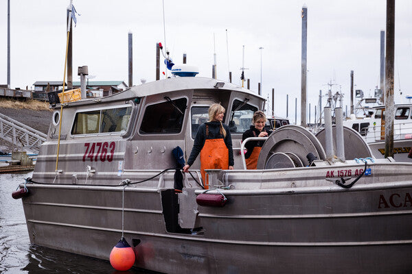 Emma and Claire standing on their fishing boat at dock