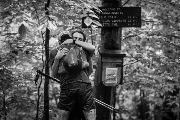 Ben and Owen hugging at the sign marking the end of the Long Trail