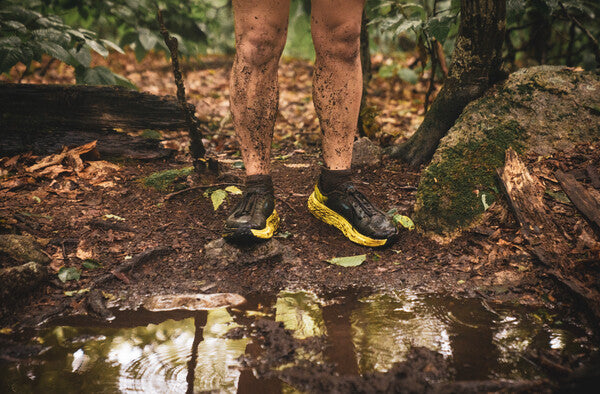 Ben's very muddy feet in darn tough socks, about to cross a stream