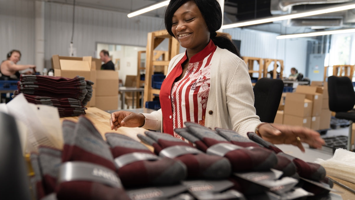 A darn tough employee in front of stacks of freshly knit socks