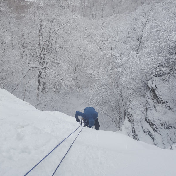 Ice climber coming up a line in the middle of heavy snowfall