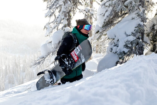 Jake standing in a snow drift carrying his snowboard