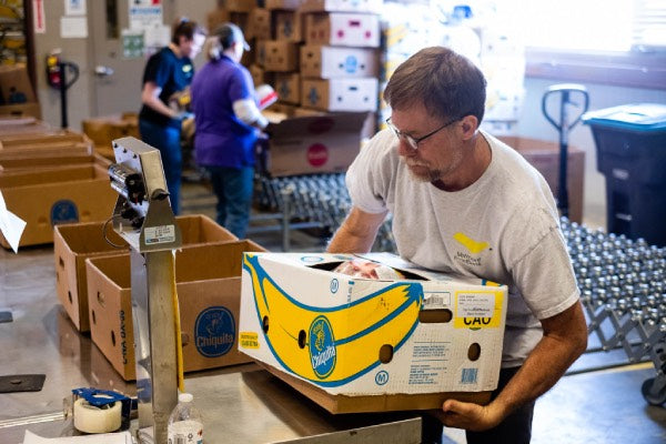 A Vermont foodbank volunteer lifting boxes of food