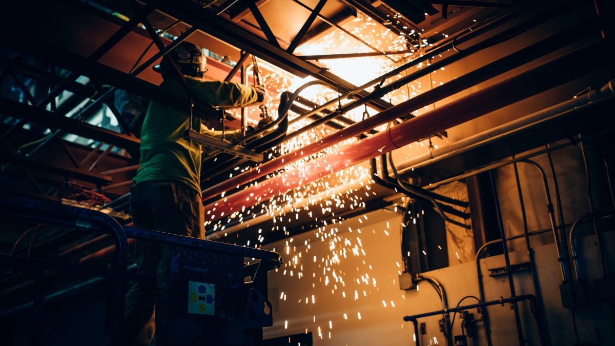 Welder working on pipe, sparks flying, good thing he's wearing fire resistant socks from darn tough