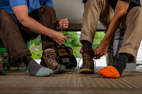 Two workers putting on leather boots over steel toe socks