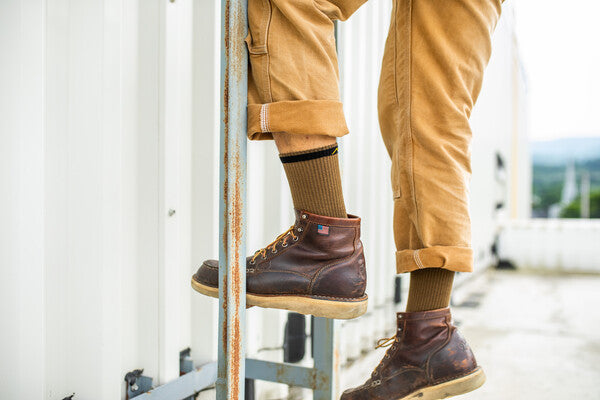 Close up on feet climbing ladder in leather boots and darn tough work socks