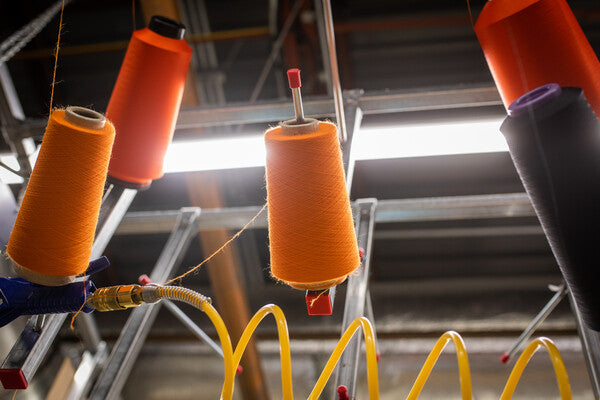 Cones of yarns hanging up at the Darn Tough Mill