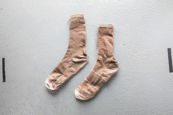 A pair of brown work socks with holes we replaced under our guarantee