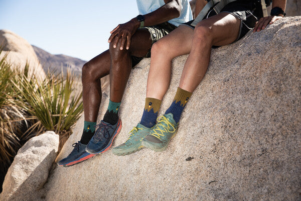 Two hikers seated on rocks both wearing merino wool number 2 hiking socks