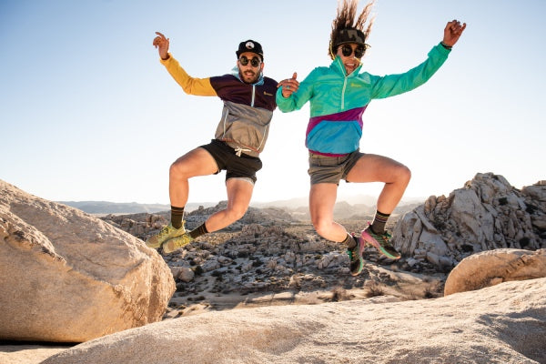 Two people busting a dance move on a mountain, clicking their heels