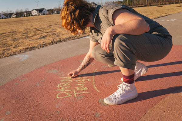 Woman drawing with chock wearing darn tough soft socks