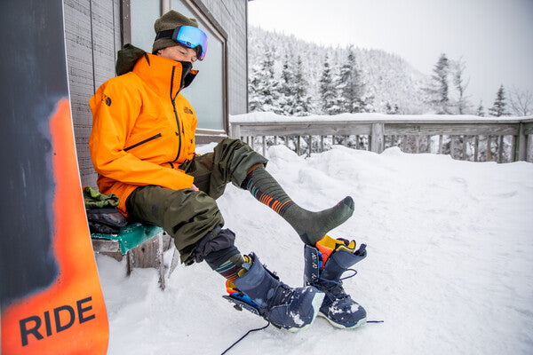 Jake putting on snowboard boots over his merino wool socks
