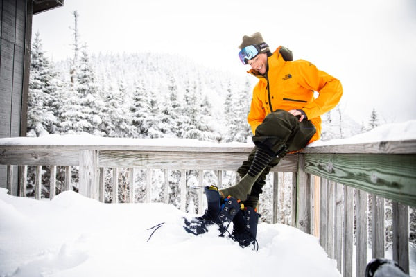 Snowboarder Jake blauvelt putting on snowboard boots over darn tough ski and ride socks