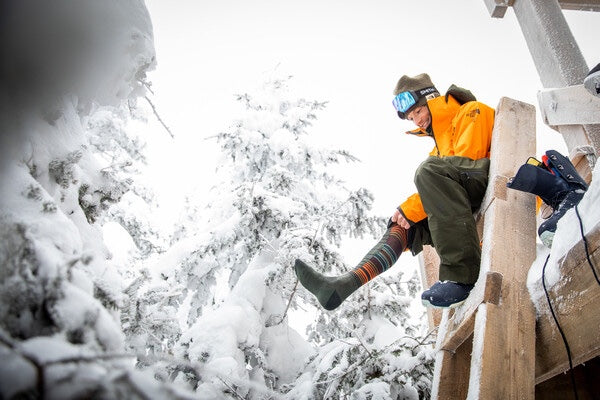 Jake Blauvelt pulling on the Backwoods snowboard socks, which he helped design