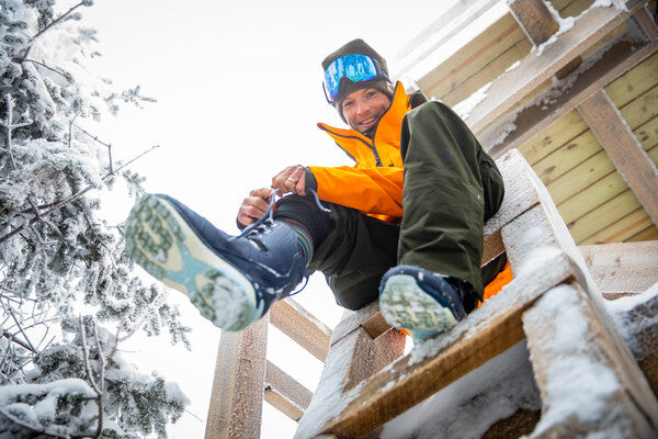 Professional snowboarder Jake Blauvelt pulling on his snowboard boots