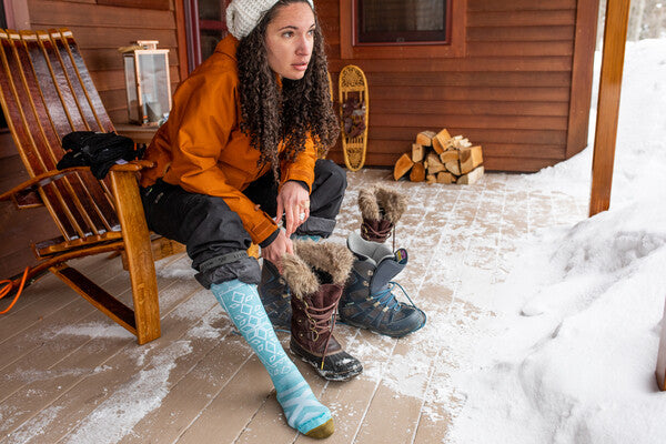 Lady snowboarder switching from her winter boots to her snowboard boots showing her blue snowboard socks