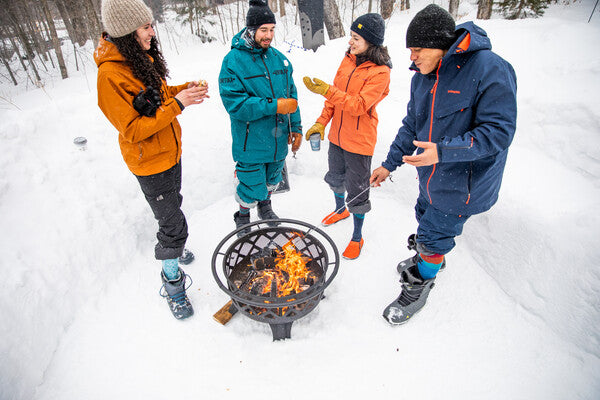 A group of friends outside in the cold winter wearing Darn Tough socks around a fire