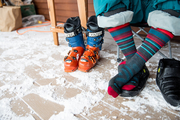 Feet wearing durable darn tough ski socks, taking a break from the mountain