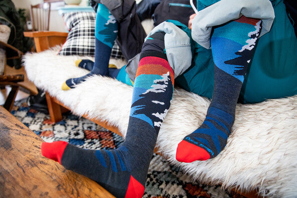 Skiers in the lodge warming up wearing matching couple's Traverse socks